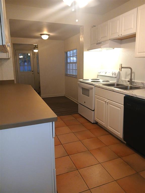 A kitchen features white cabinets, a white stove, a double sink, and terracotta tile flooring — 5410 70TH WAY N, ST PETERSBURG, FL
