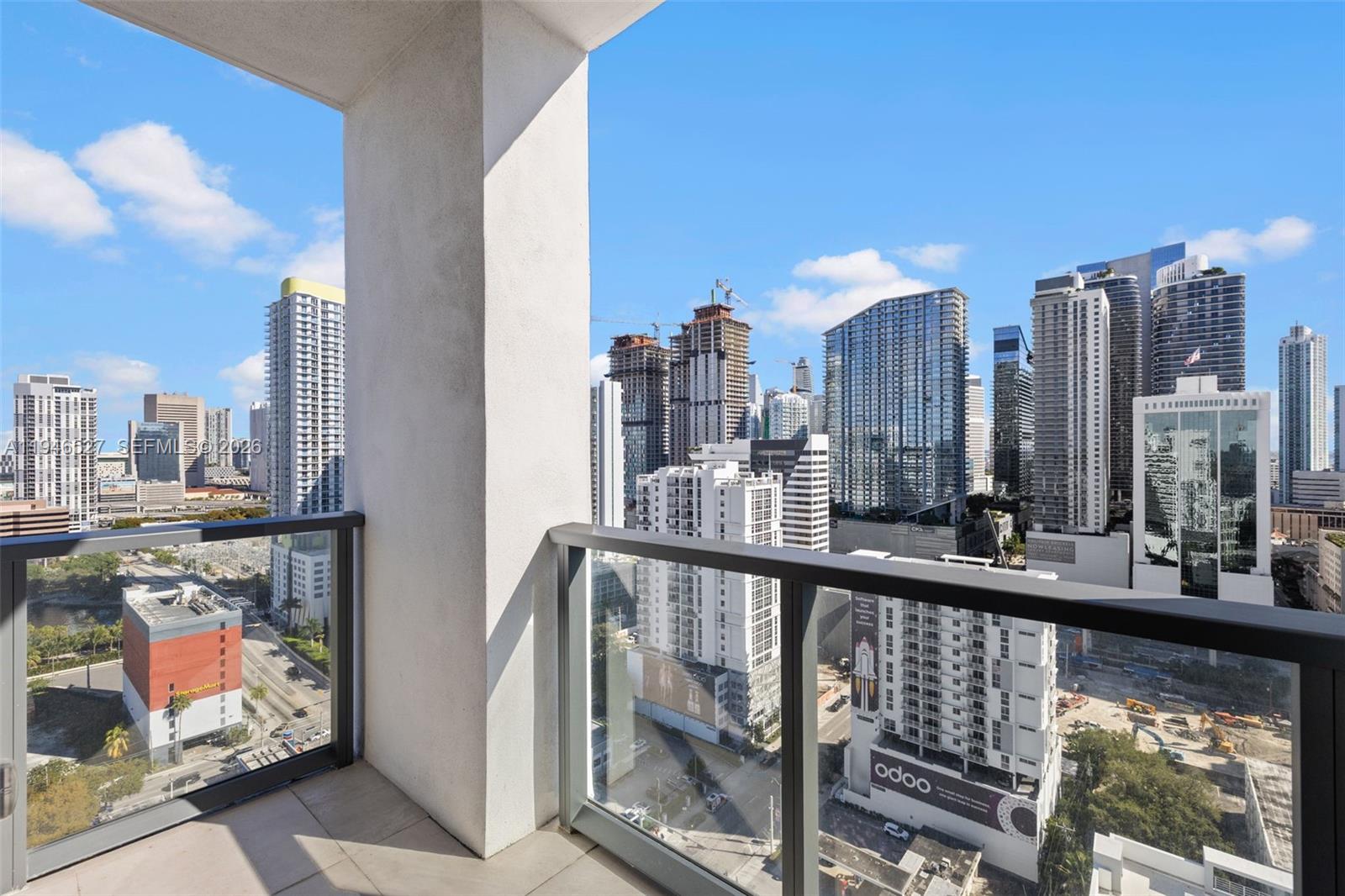 A balcony with a glass railing overlooks a dense city skyline under a blue sky — 239 SW 9th St # 2304, Miami FL 33130, MIAMI, FL