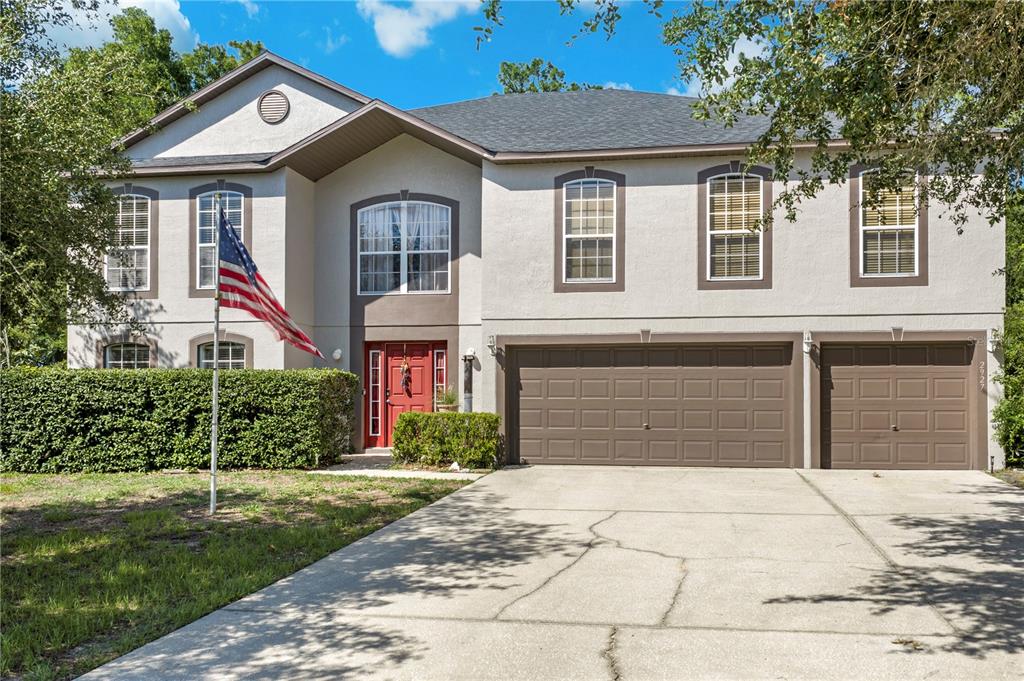 A two-story house with a beige stucco exterior, brown trim, and a three-car garage — 2927 SE 46TH AVENUE, OCALA, FL