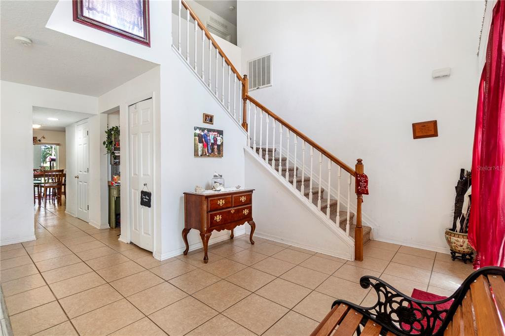 A tiled entryway features a wooden staircase with white railings and a small wooden chest — 2927 SE 46TH AVENUE, OCALA, FL