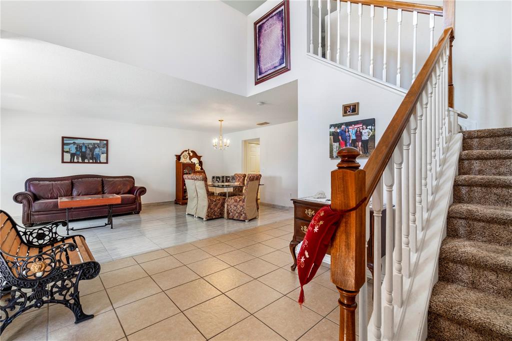 A living and dining area with tiled floors, a staircase, and a high ceiling — 2927 SE 46TH AVENUE, OCALA, FL