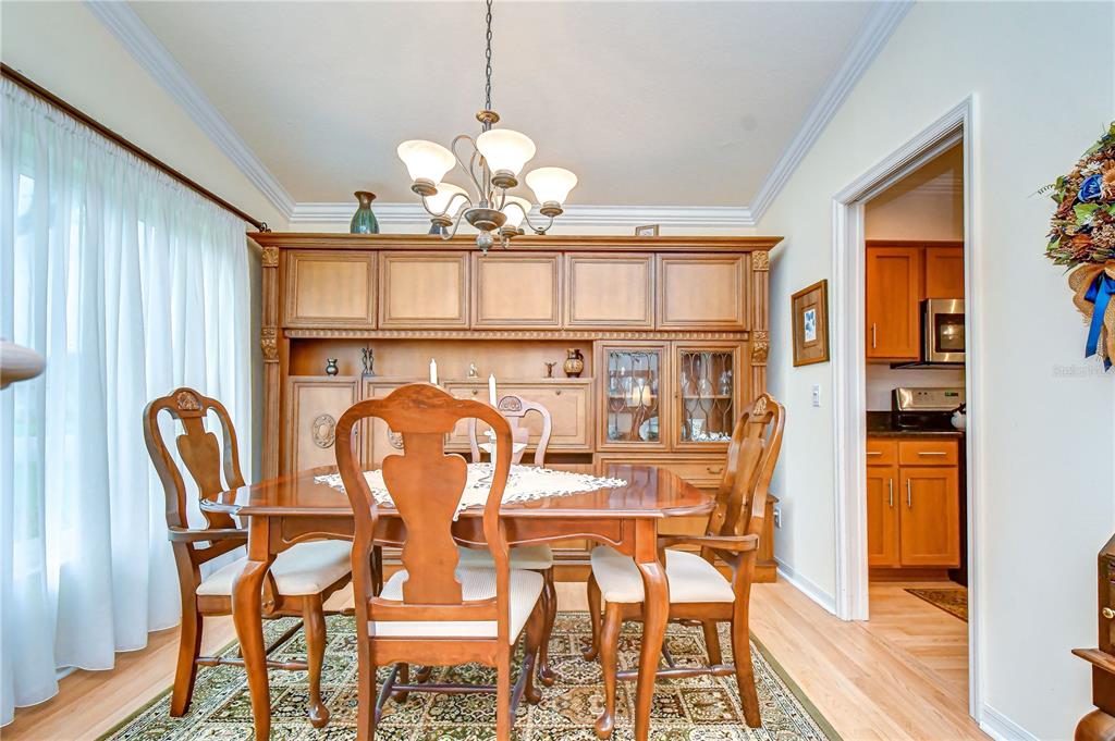 A dining room features a wooden hutch, a table with four chairs, and a chandelier — 5602 ROCKFIELD LOOP, VALRICO, FL