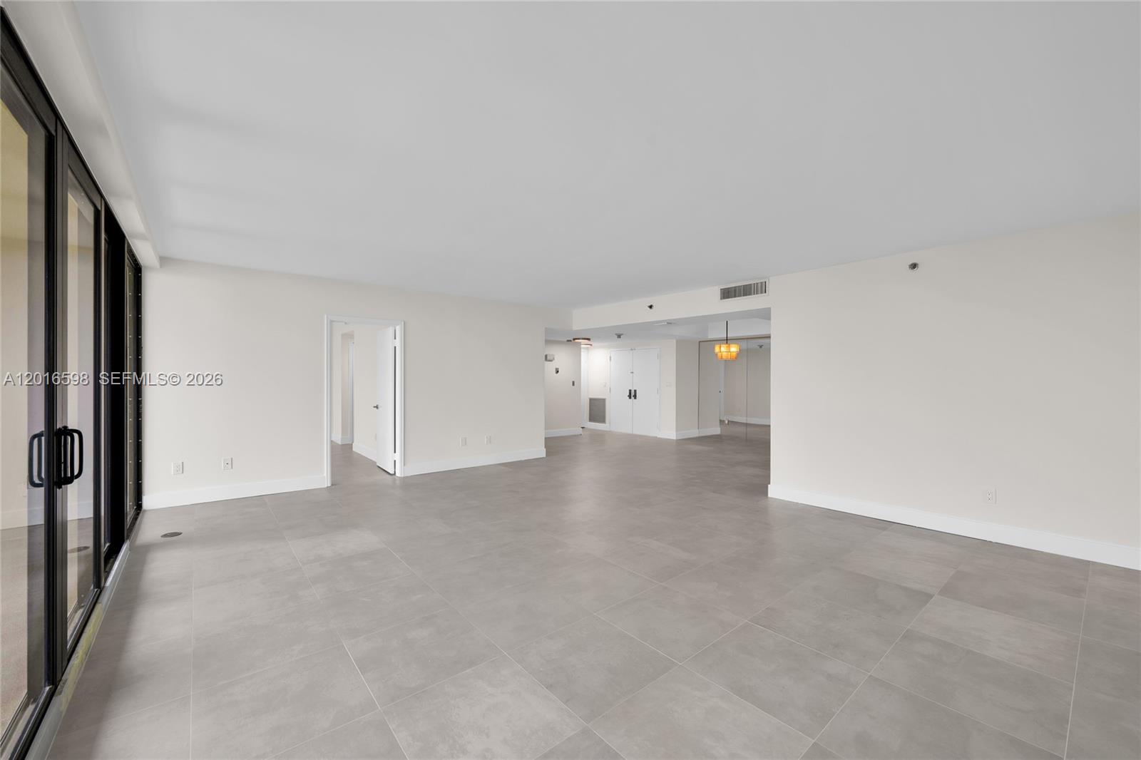 An empty, open-concept living area features large gray floor tiles and white walls — 11113 Biscayne Blvd # 1253, Miami FL 33181, MIAMI, FL