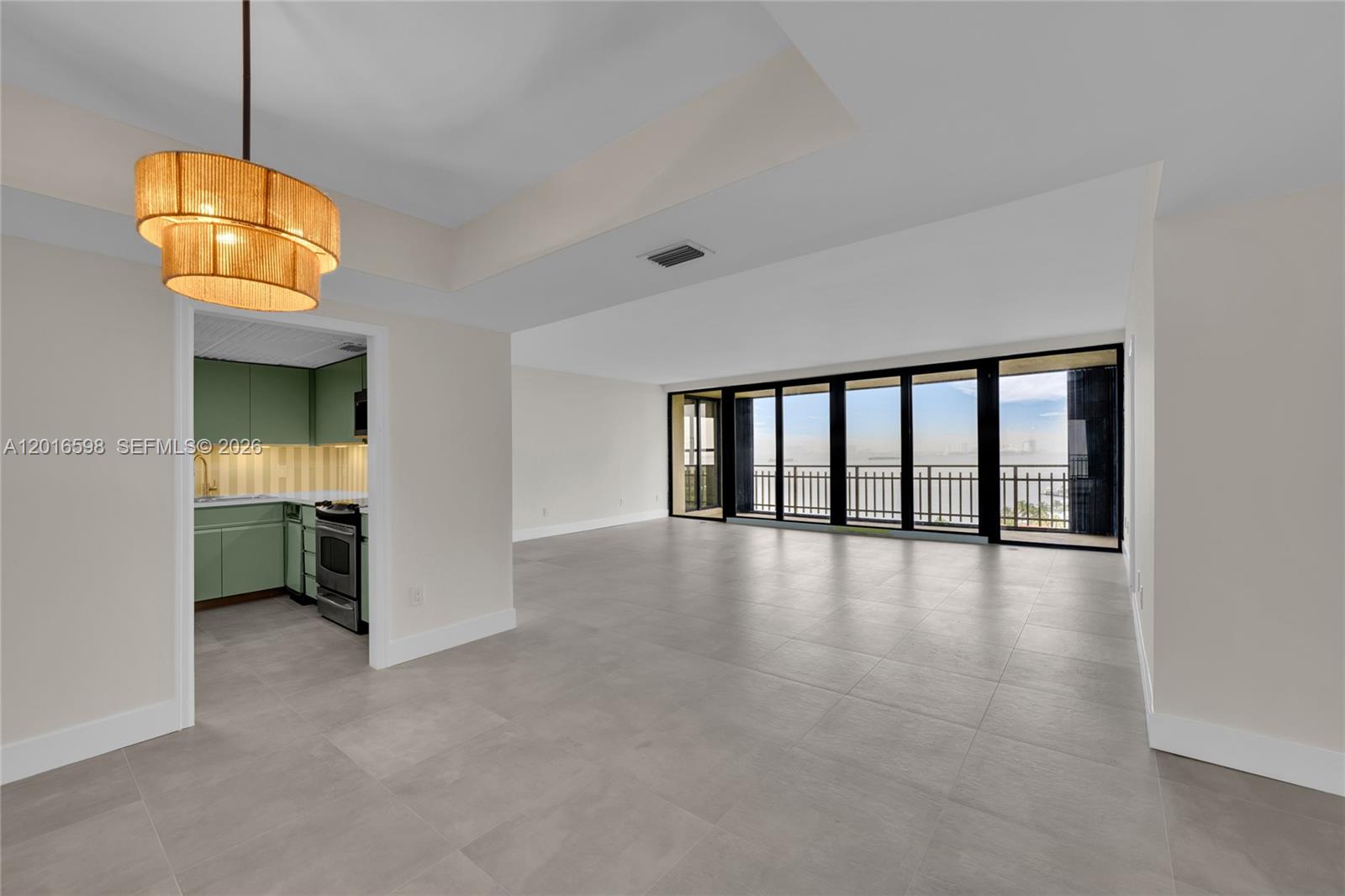 An open living area with large windows, tile flooring, and an adjacent green kitchen — 11113 Biscayne Blvd # 1253, Miami FL 33181, MIAMI, FL