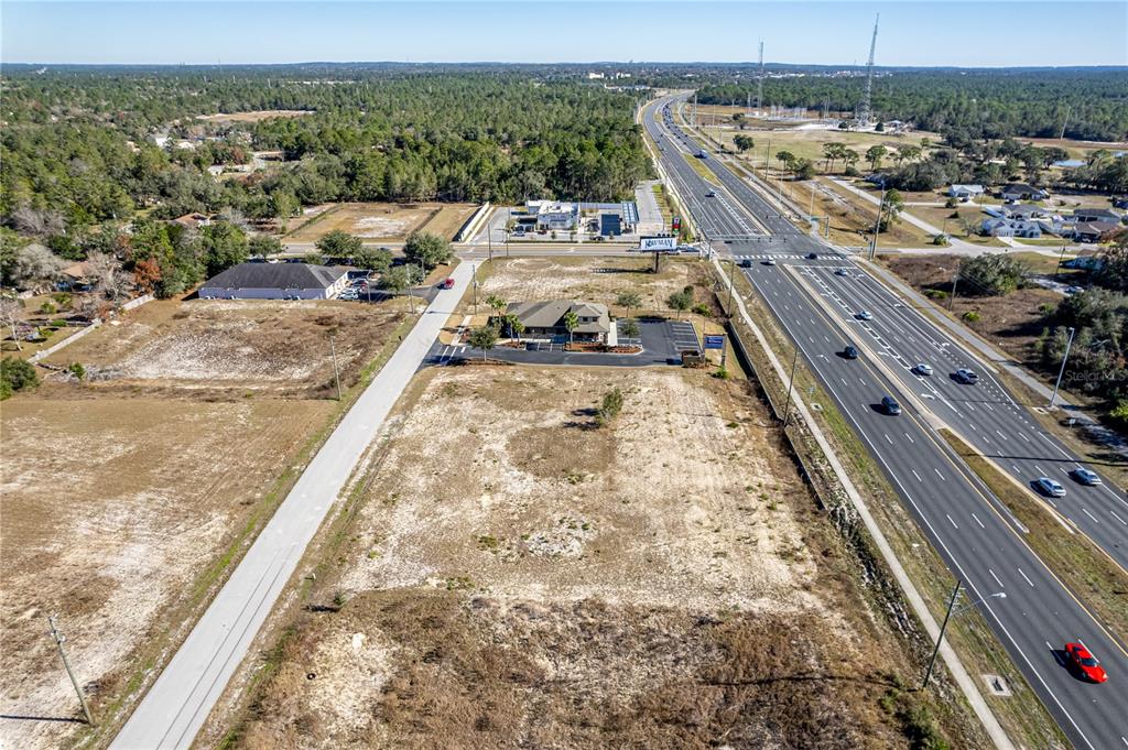 An aerial view shows a vacant commercial lot adjacent to a highway and a small building — 10260 YALE AVENUE, WEEKI WACHEE, FL