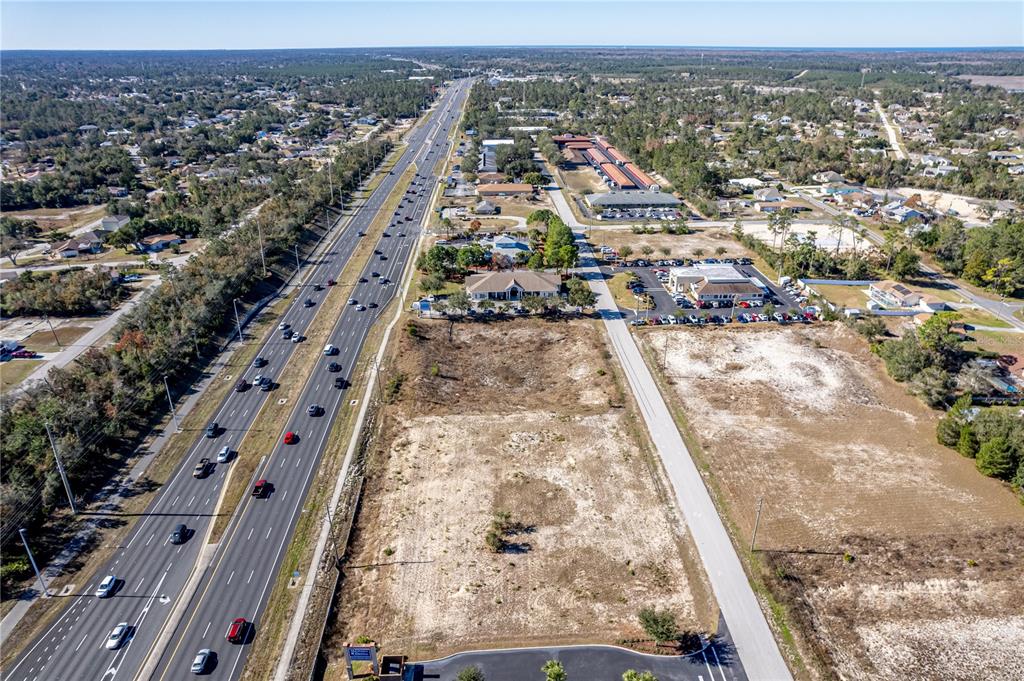 An aerial view shows a vacant lot adjacent to a highway and commercial buildings — 10260 YALE AVENUE, WEEKI WACHEE, FL