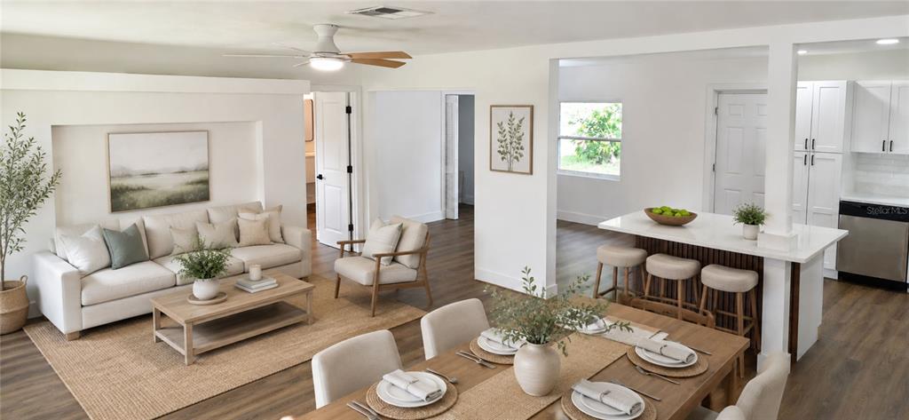 An open-concept living, dining, and kitchen area featuring white cabinetry, wood flooring, and neutral furniture — 180 N KENTUCKY AVENUE, UMATILLA, FL