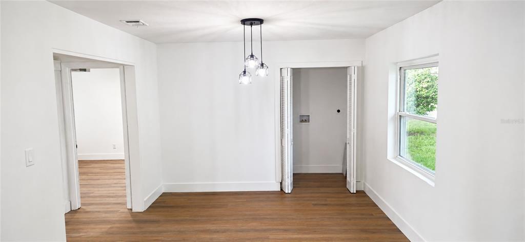 A room with white walls, wood-look flooring, a pendant light, and a laundry closet — 180 N KENTUCKY AVENUE, UMATILLA, FL