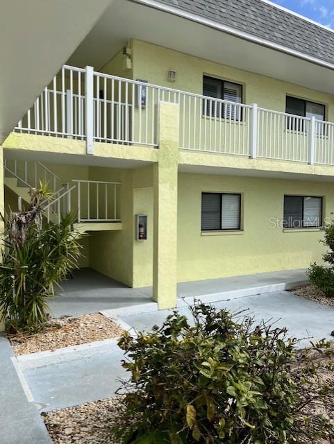 Exterior view of a two-story yellow apartment building with white railings and stairs — 6703 MIDNIGHT PASS ROAD UNIT 217, SARASOTA, FL