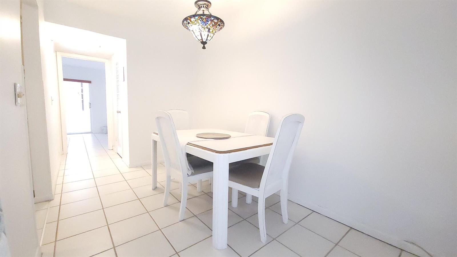 A dining area with a white table, four chairs, and a stained-glass pendant light — 319 Chatham P, West Palm Beach FL 33417, WEST PALM BEACH, FL