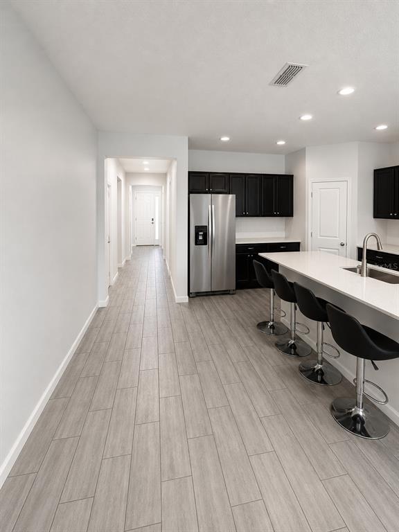 A kitchen with black cabinets, stainless steel appliances, and a white island with bar stools — 124 BELLA VERANO WAY, DAVENPORT, FL