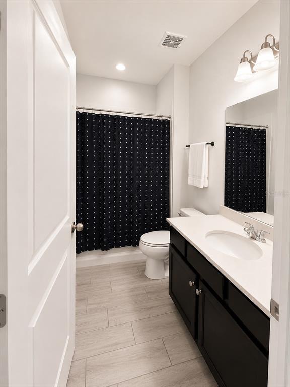 A bathroom features a dark vanity, a polka-dot shower curtain, and light-colored tile flooring — 124 BELLA VERANO WAY, DAVENPORT, FL