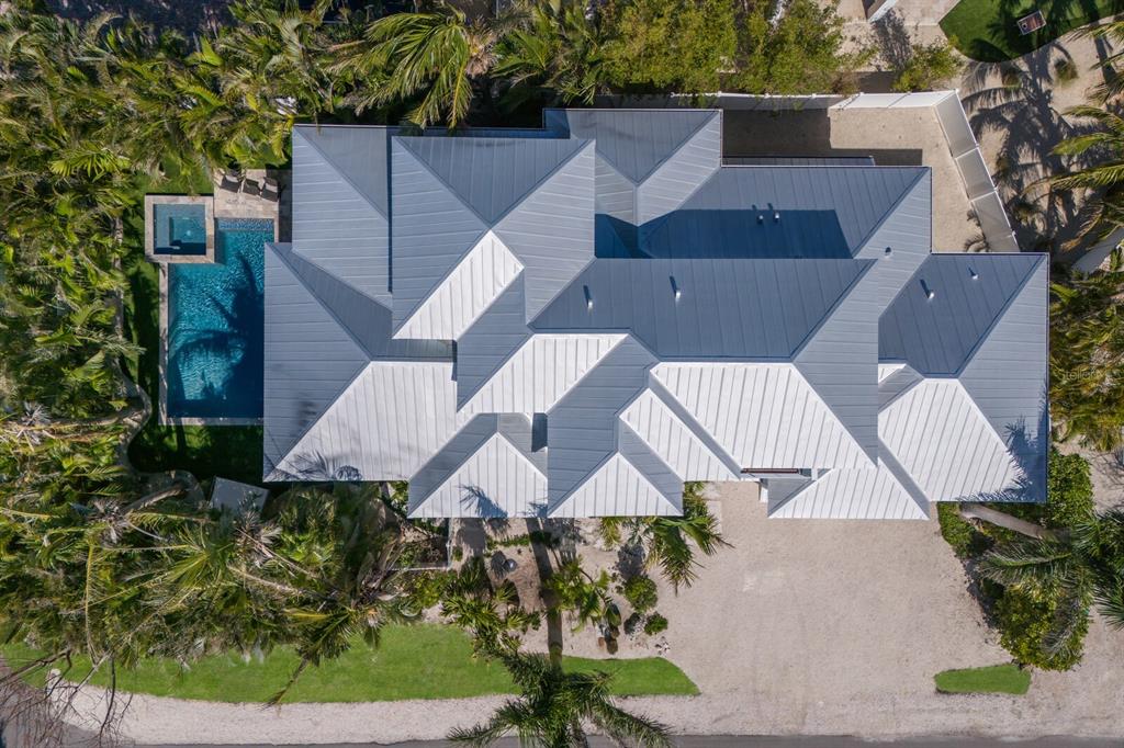 An aerial view shows a house with a multi-faceted metal roof and a backyard pool — 222 WILLOW AVENUE, ANNA MARIA, FL