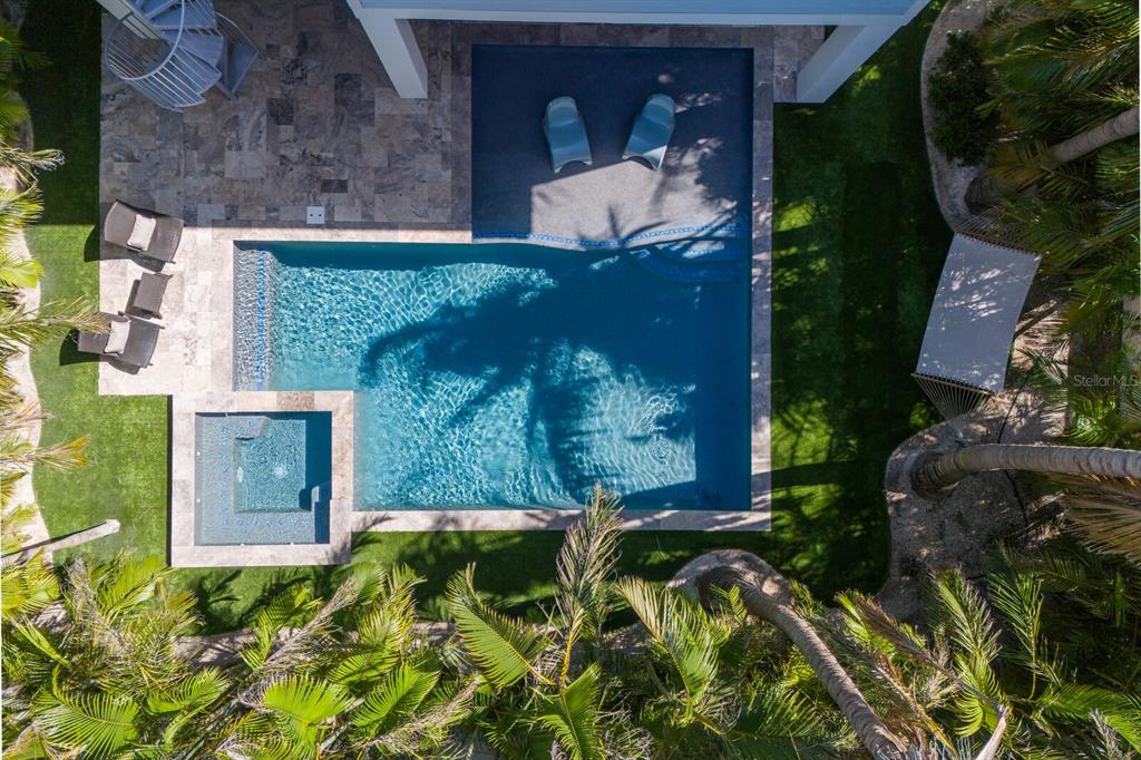 An aerial view of a backyard featuring a swimming pool, spa, and stone patio area — 222 WILLOW AVENUE, ANNA MARIA, FL