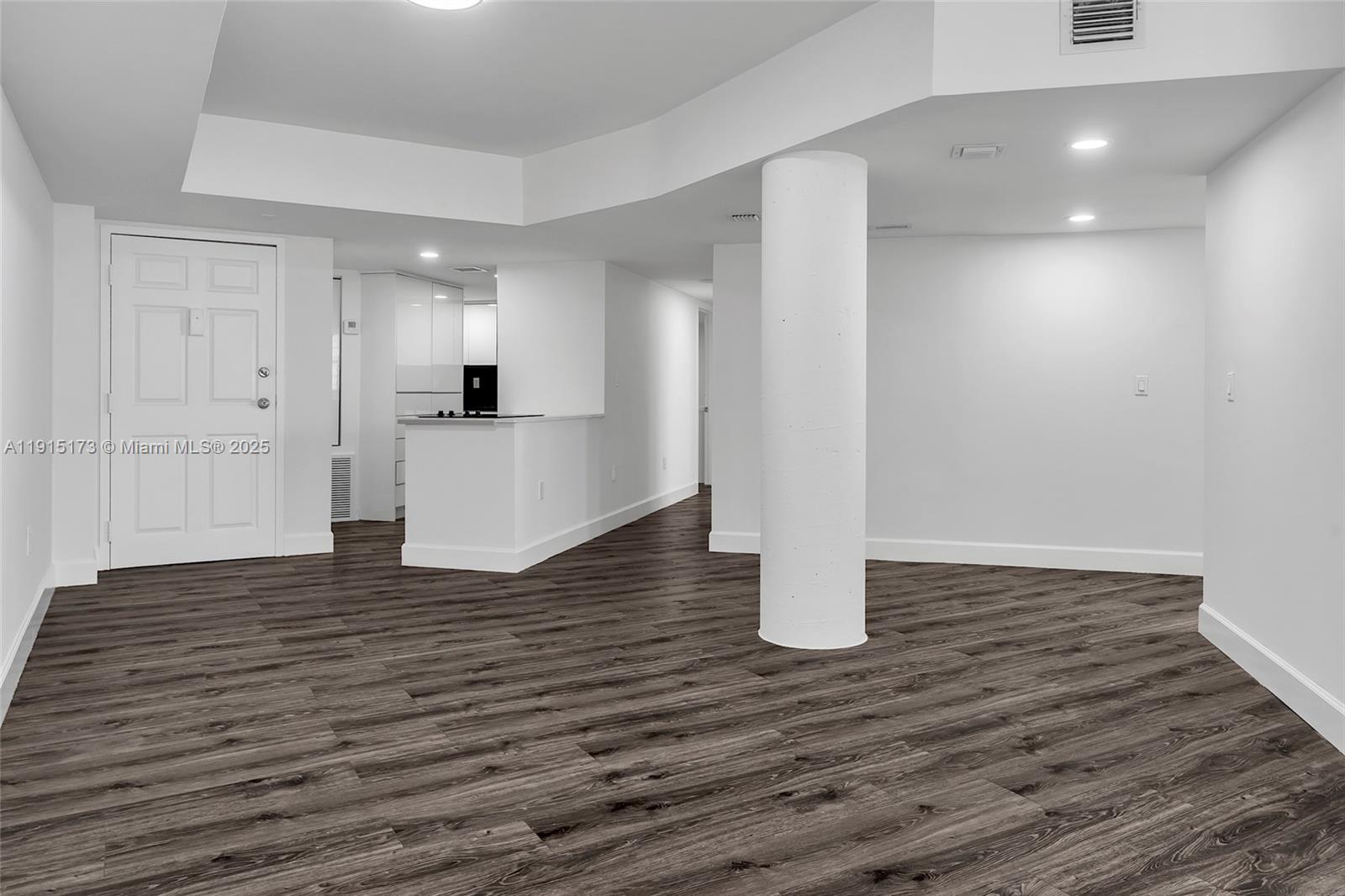 An open-concept living area features white walls, dark wood-look flooring, and a structural column — 825 Brickell Bay Dr # 1942, Miami FL 33131, MIAMI, FL