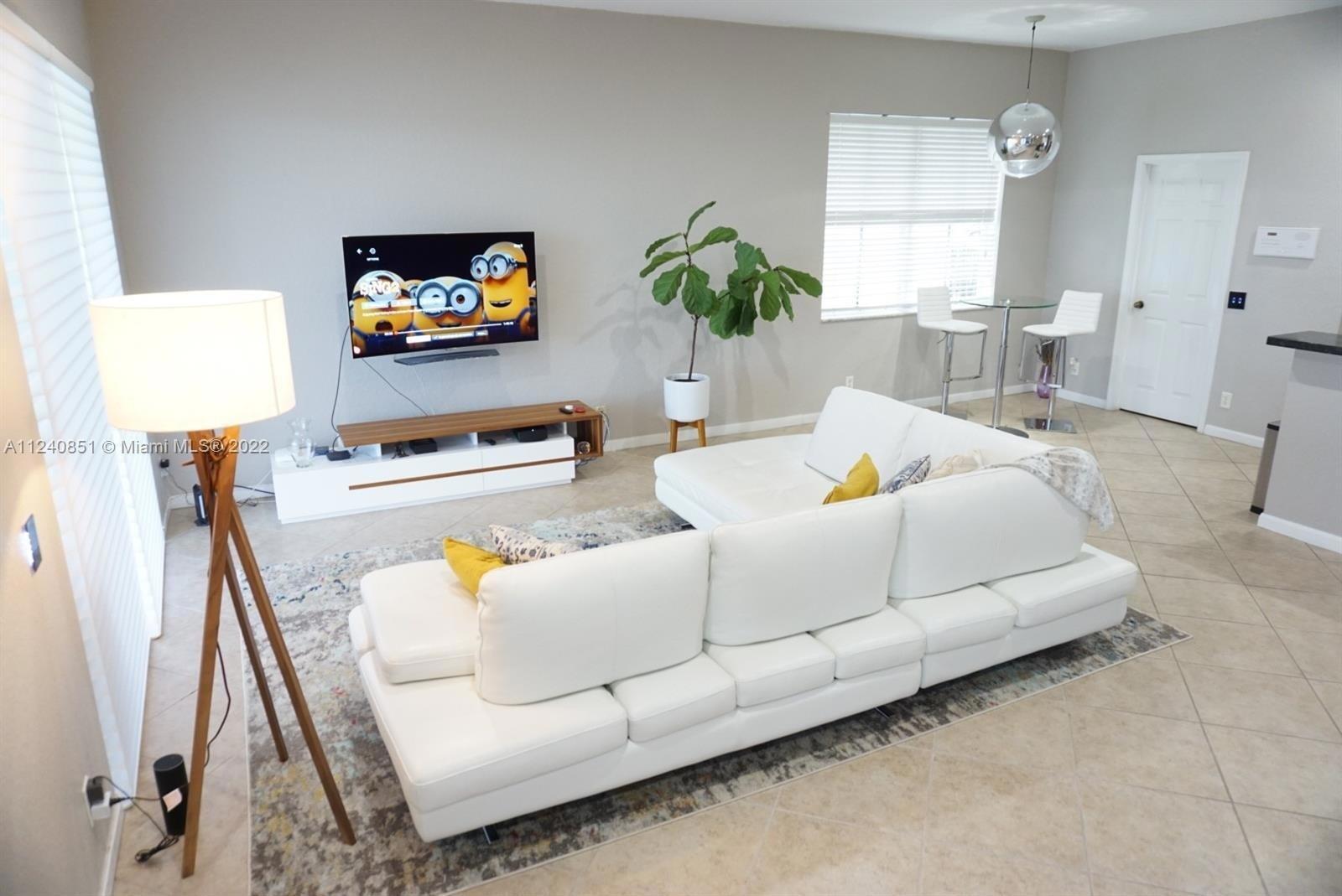 A living room features a white sectional sofa, a wall-mounted television, and a tripod floor lamp — 878 Lavender Circle # 878, Weston FL 33327, WESTON, FL