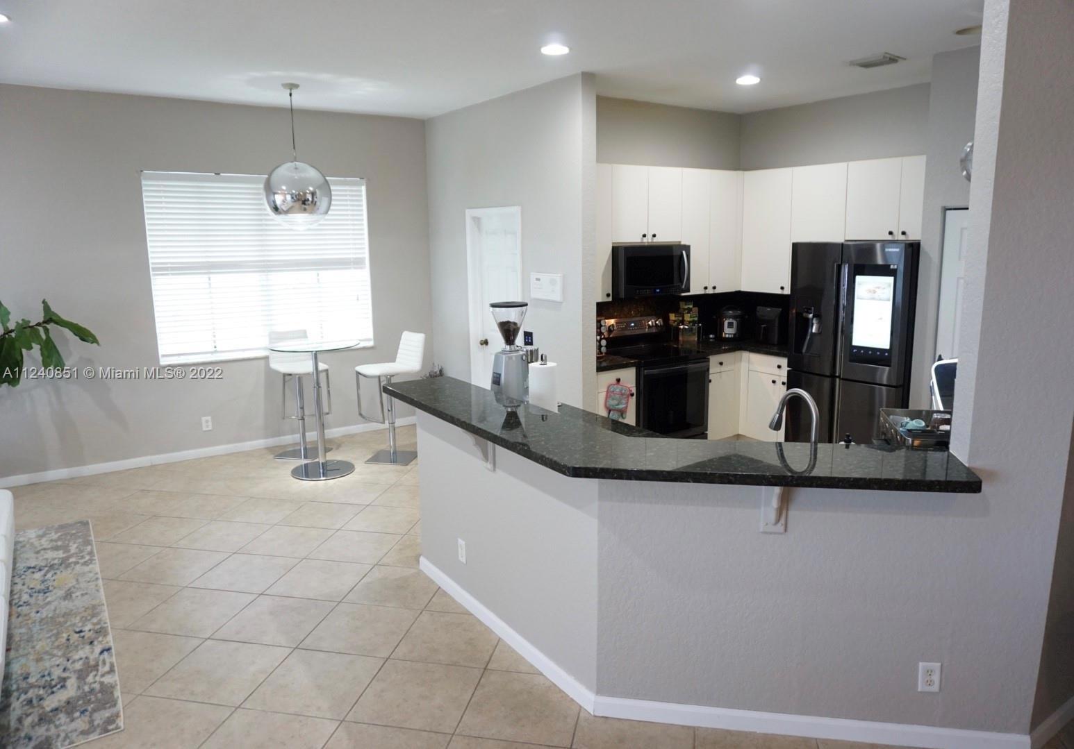 A kitchen features white cabinets, black appliances, and a dark granite breakfast bar — 878 Lavender Circle # 878, Weston FL 33327, WESTON, FL