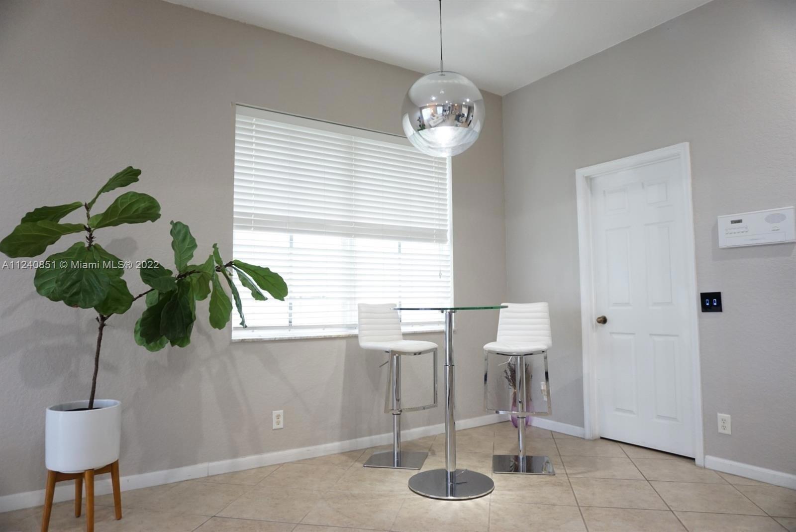 A small dining area features a glass table, two white bar stools, and a pendant light — 878 Lavender Circle # 878, Weston FL 33327, WESTON, FL
