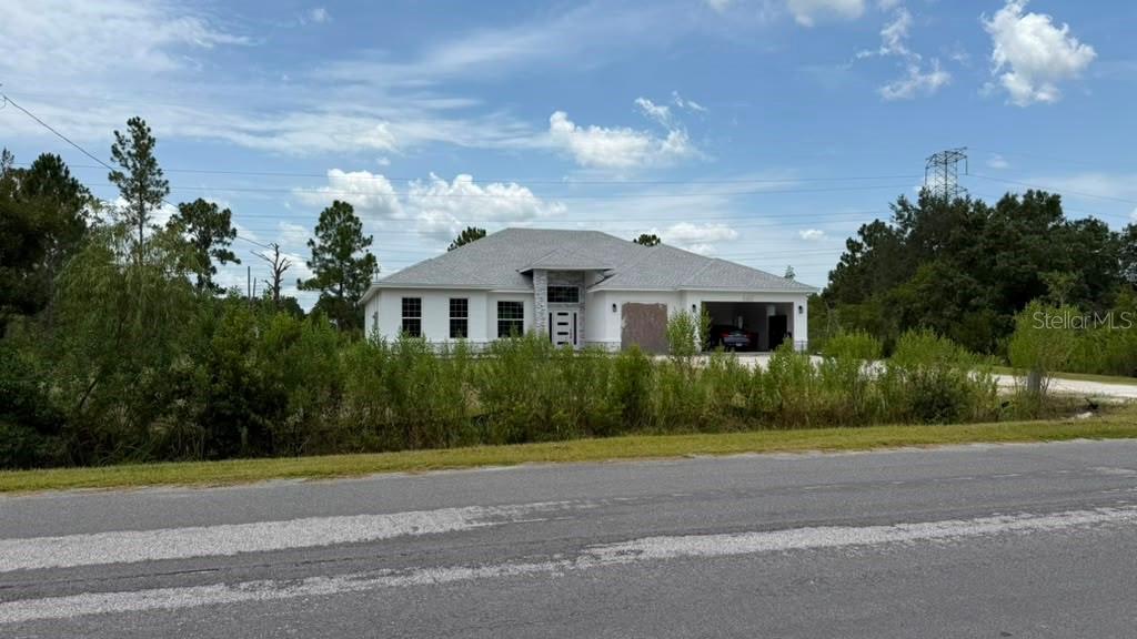 A newly constructed single-story white house with a gray roof sits behind a grassy lot — 0 NETTLETON STREET, ORLANDO, FL