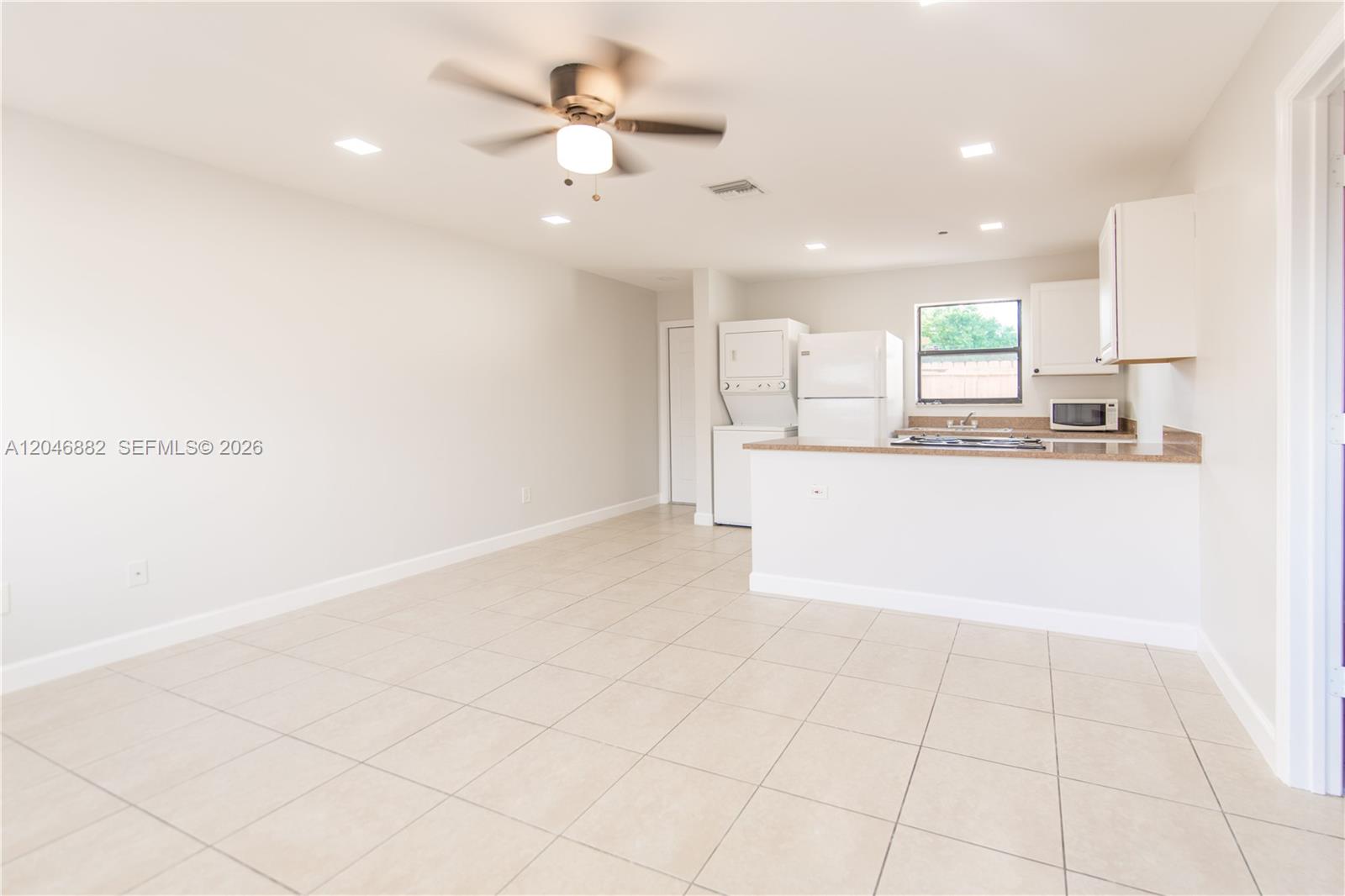 An open-concept kitchen and living area features tile flooring, white cabinetry, and a ceiling fan — 1804 My Pl, West Palm Beach FL 33417, WEST PALM BEACH, FL
