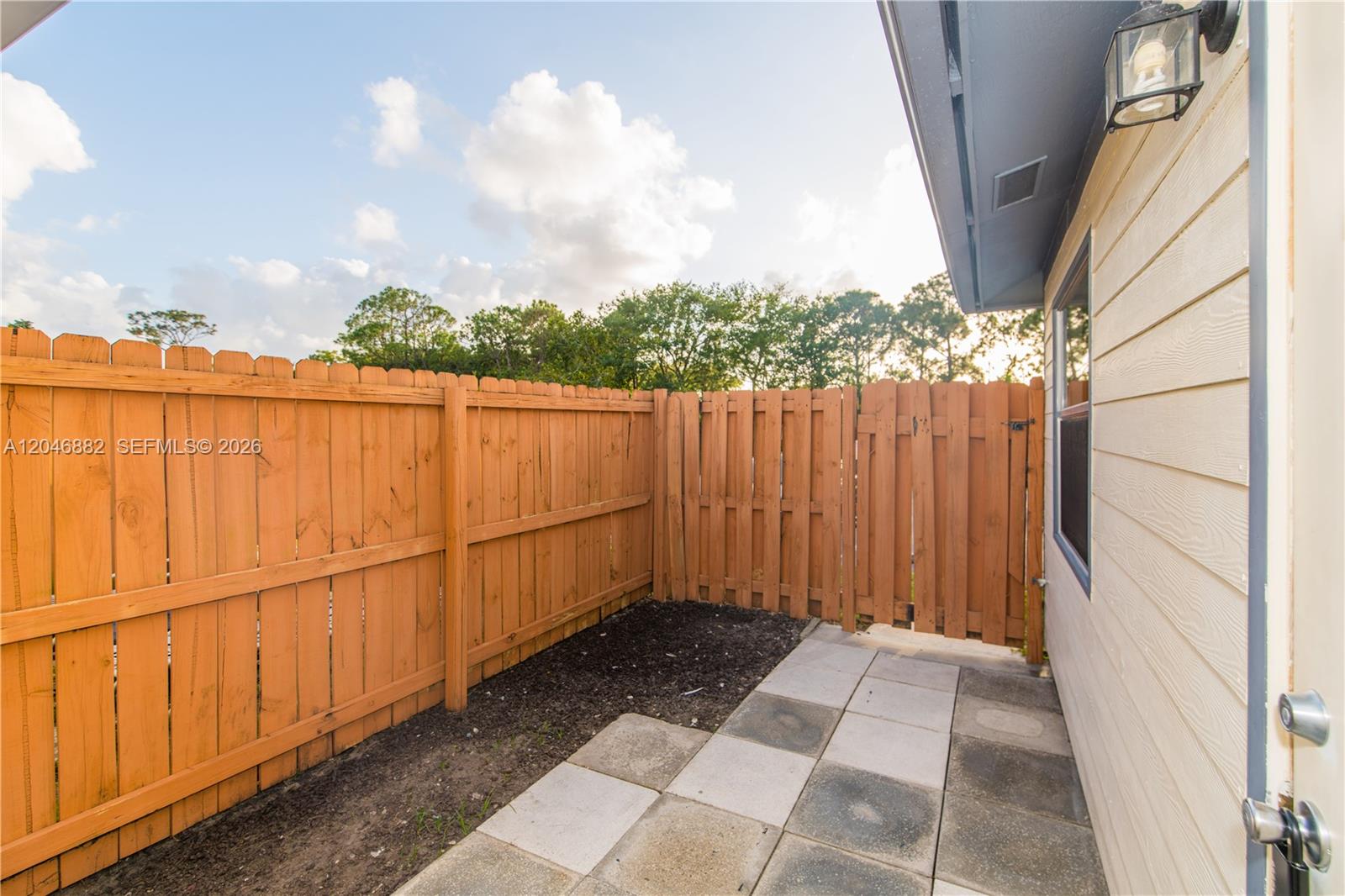 A small patio with pavers and a wooden fence sits beside the exterior wall — 1804 My Pl, West Palm Beach FL 33417, WEST PALM BEACH, FL