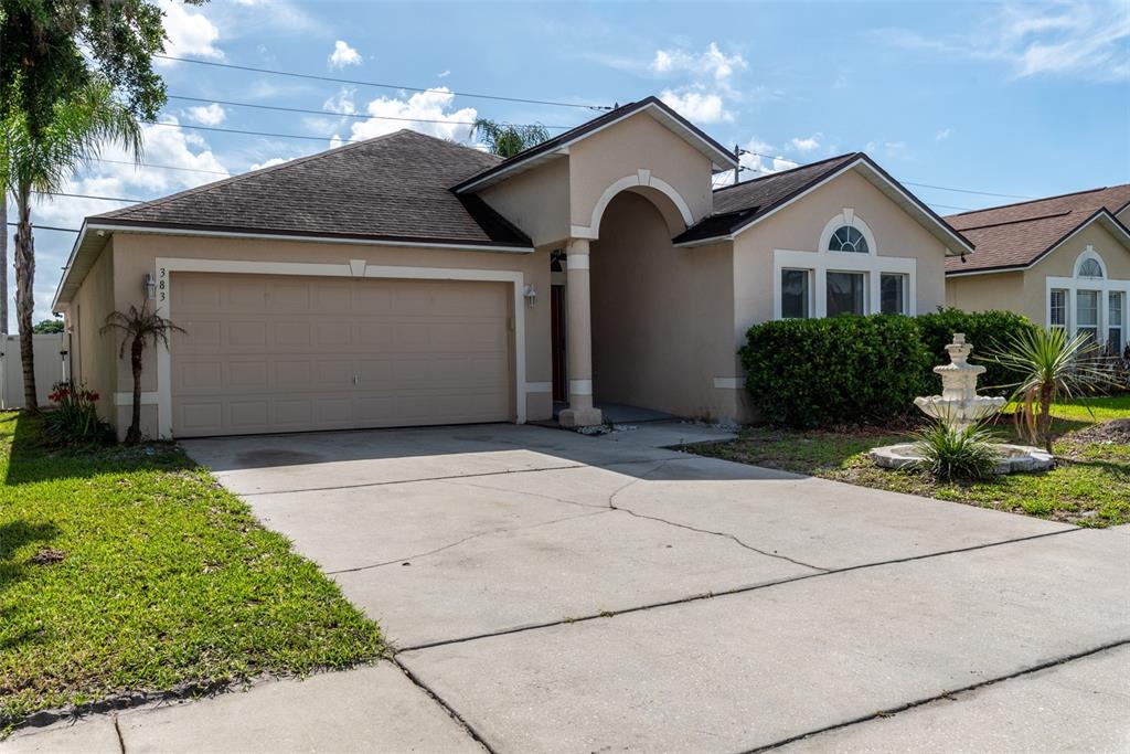 A single-story house with a beige stucco exterior, a two-car garage, and a front fountain — 383 FAIRFIELD DRIVE, SANFORD, FL
