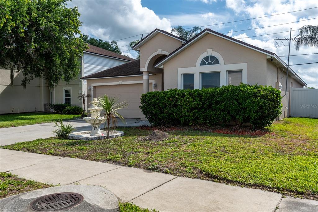 A tan single-story house with a two-car garage, a front fountain, and a large hedge — 383 FAIRFIELD DRIVE, SANFORD, FL