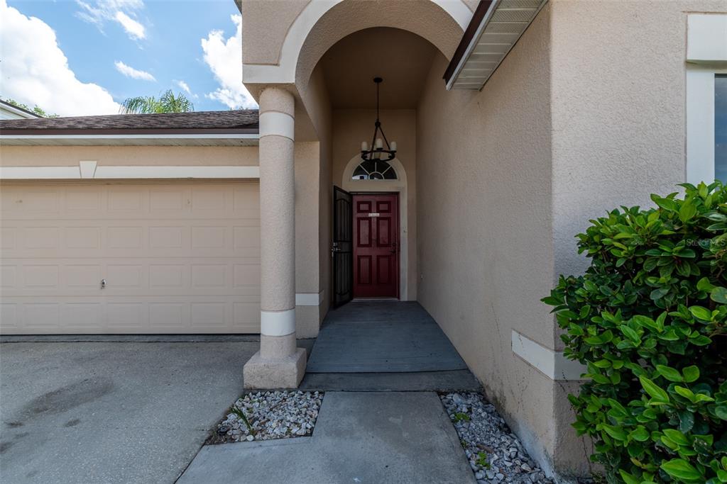 A beige house exterior features a red front door, a garage, and a covered entryway — 383 FAIRFIELD DRIVE, SANFORD, FL