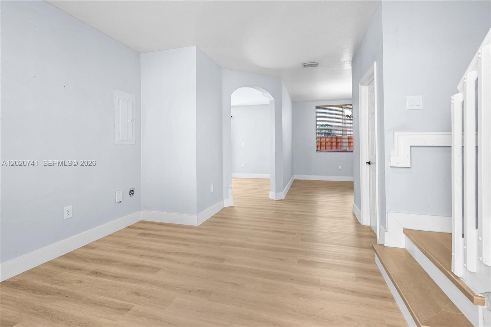 An empty room with light wood-look flooring, white walls, and a staircase on the right — 1595 NE 33rd Rd # 3, Homestead FL 33033, HOMESTEAD, FL
