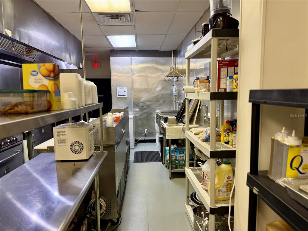 A commercial kitchen features stainless steel counters, shelving units, and a rear exit door — 12149 S WILLIAMS STREET UNIT 3, DUNNELLON, FL