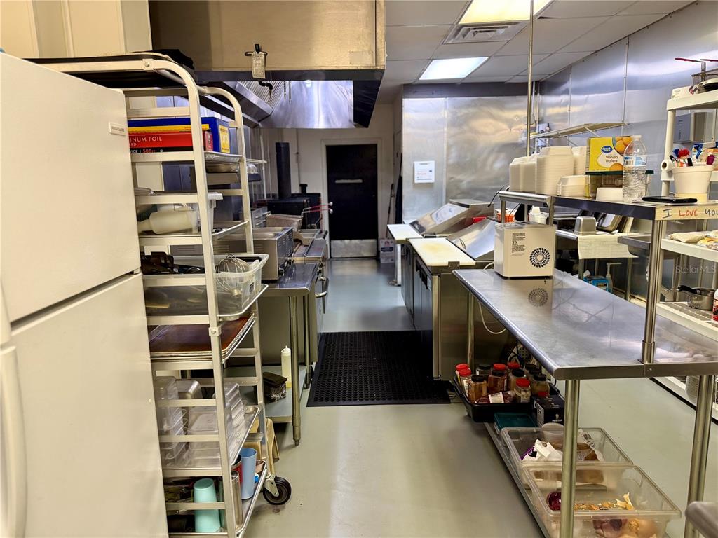 A commercial kitchen features stainless steel prep tables, a metal shelving unit, and cooking equipment — 12149 S WILLIAMS STREET UNIT 3, DUNNELLON, FL