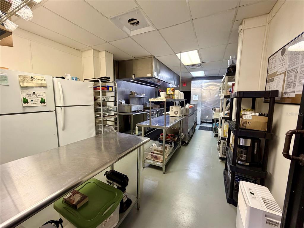 A commercial kitchen features stainless steel prep tables, a refrigerator, and metal shelving units — 12149 S WILLIAMS STREET UNIT 3, DUNNELLON, FL
