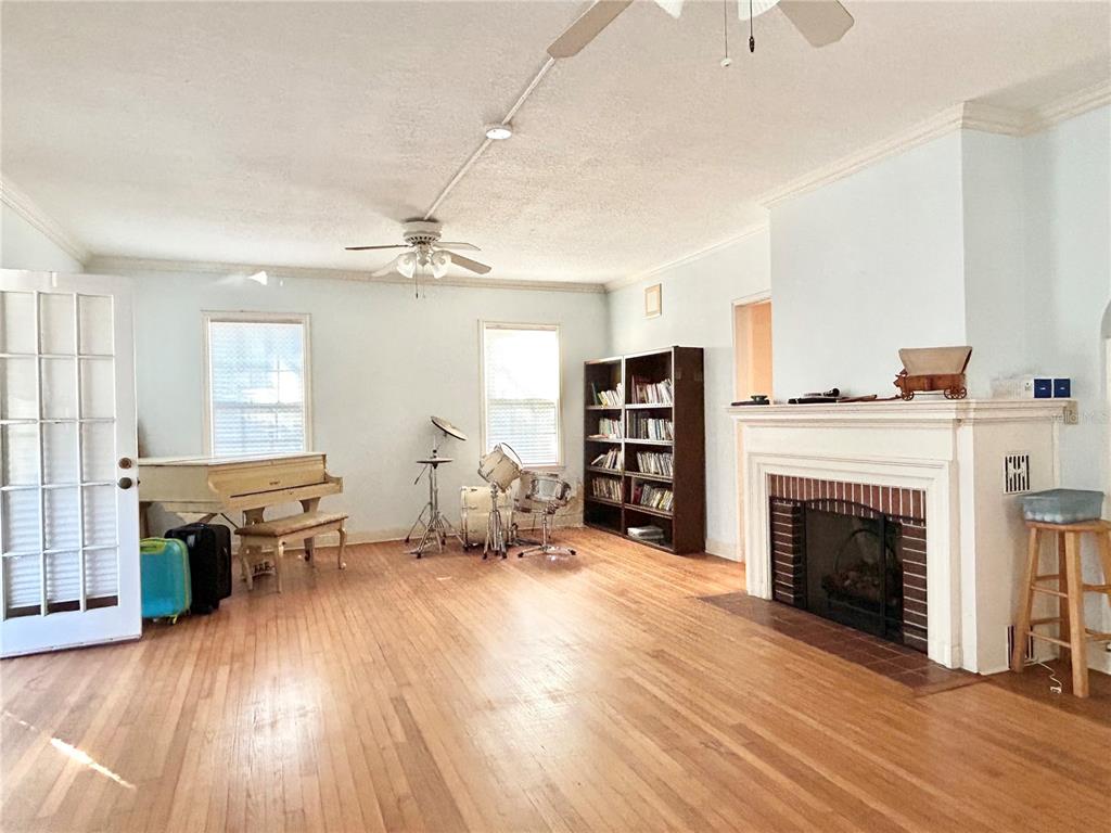 A living room features hardwood floors, a fireplace, a piano, a drum set, and bookshelves — 1105 HERNDON STREET, LEESBURG, FL