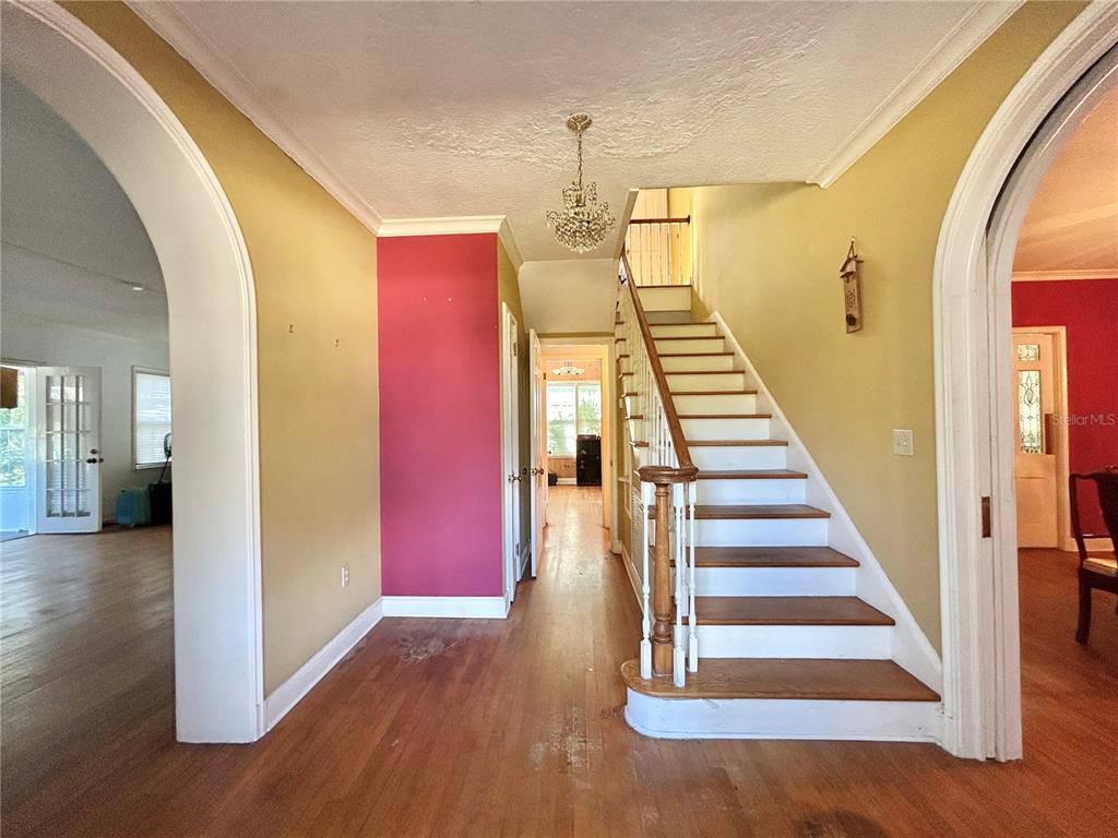 An entryway features hardwood floors, a staircase with white railings, and a pink accent wall — 1105 HERNDON STREET, LEESBURG, FL