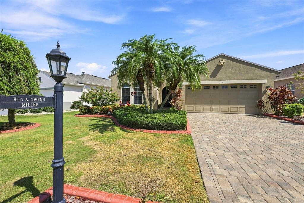 A single-story house with a paved driveway, a palm tree, and a decorative lamp post — 441 NOBLE FAIRE DRIVE, SUN CITY CENTER, FL