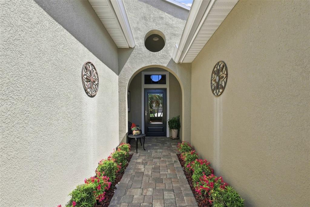 A paved walkway leads to a front door framed by an arched entryway and landscaping — 441 NOBLE FAIRE DRIVE, SUN CITY CENTER, FL
