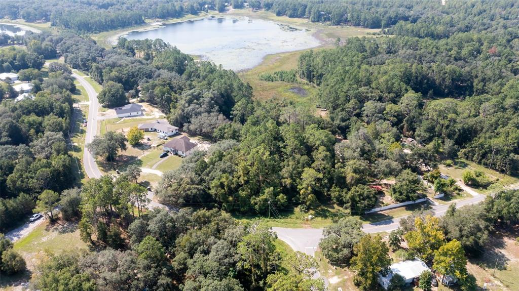 An aerial view shows a wooded residential area with a lake and several houses — 101 ASHLEY LAKE DRIVE, MELROSE, FL
