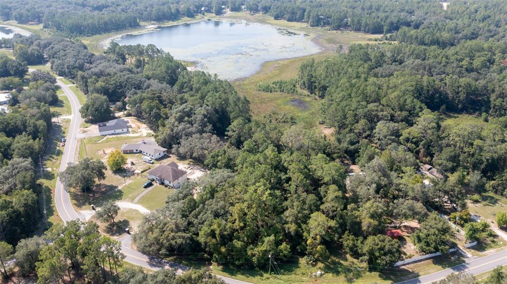 An aerial view shows houses along a curved road near a large lake and forest — 101 ASHLEY LAKE DRIVE, MELROSE, FL