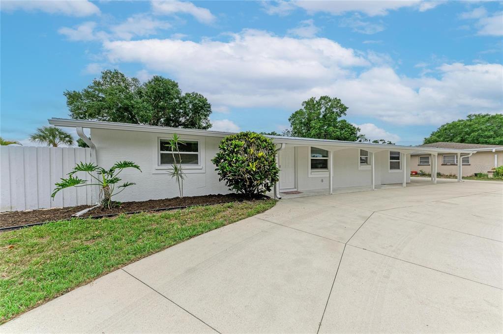 A white single-story house with a large concrete driveway and a covered carport area — 2714 DATURA STREET, SARASOTA, FL
