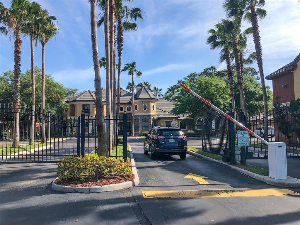 A black SUV enters a gated community through a security arm at the entrance — 2261 TUSCANY TRACE UNIT 106, PALM HARBOR, FL