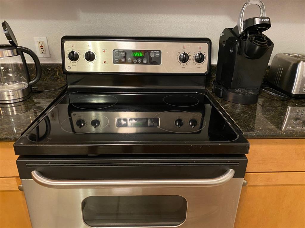 A stainless steel electric range with a glass cooktop sits between a coffee maker and kettle — 2261 TUSCANY TRACE UNIT 106, PALM HARBOR, FL
