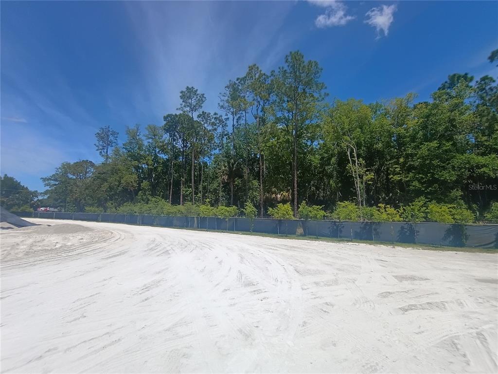A sandy, cleared lot is bordered by a tall fence and a line of trees — 79 CR-304, BUNNELL, FL