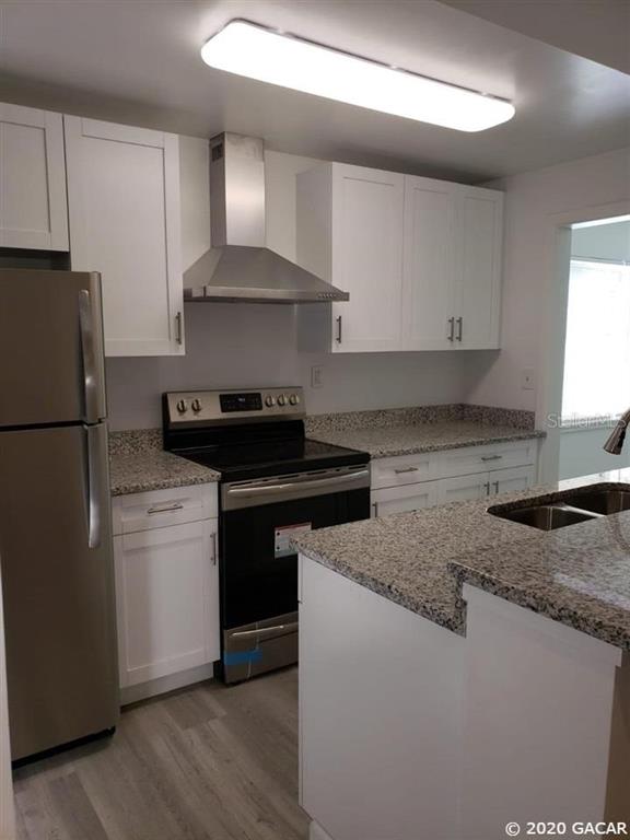 A kitchen features white cabinets, stainless steel appliances, and granite countertops — 1115 NE 5TH PLACE, GAINESVILLE, FL