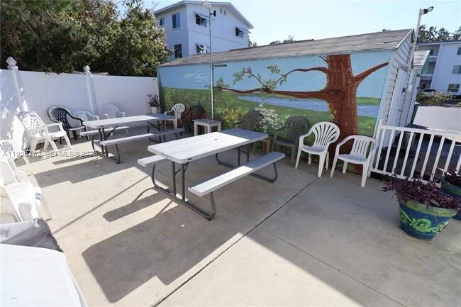 An outdoor patio features picnic tables, chairs, and a mural painted on a shed wall — 1832 Sunny Drive # 32, Bradenton FL 34207, BRADENTON, FL