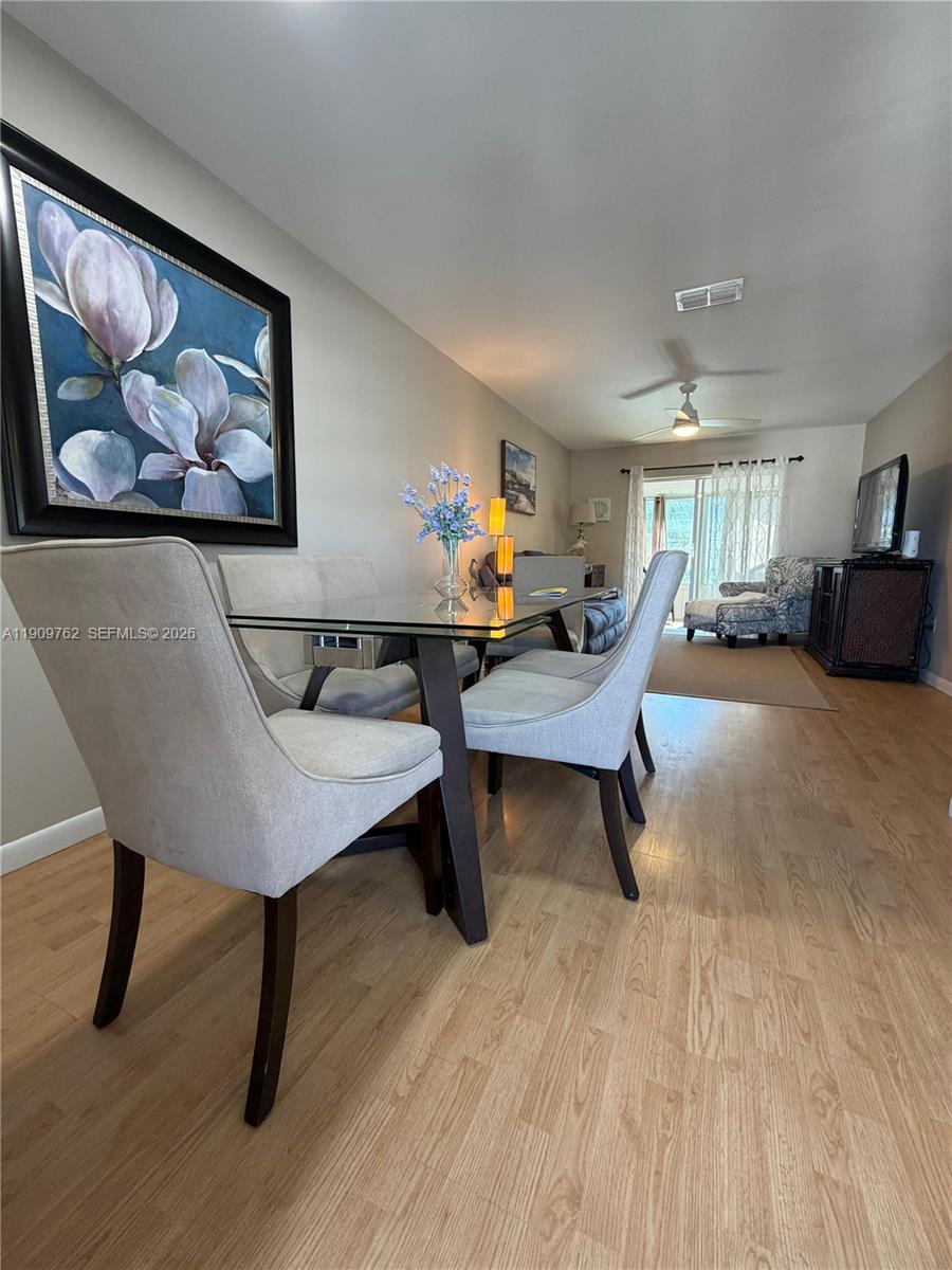 A dining area with a glass-topped table and upholstered chairs sits before a living room — 1832 Sunny Drive # 32, Bradenton FL 34207, BRADENTON, FL