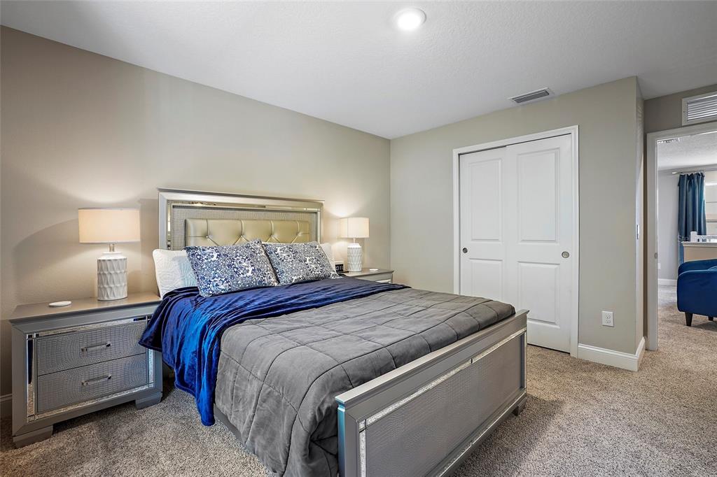 A bedroom features a bed with a grey quilt, blue throw, and mirrored nightstands — 5246 NEIL DRIVE, ST PETERSBURG, FL