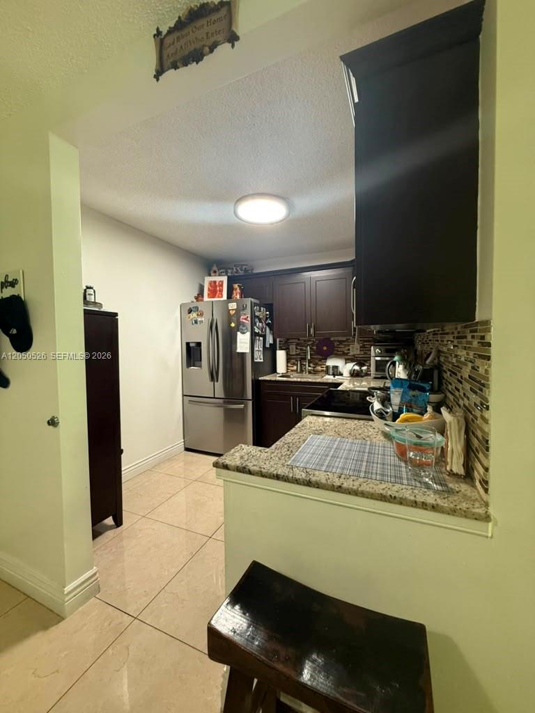 A kitchen features dark cabinetry, granite countertops, stainless steel appliances, and light-colored tile flooring — 9405 W Flagler St # 212D, Miami FL 33174, MIAMI, FL