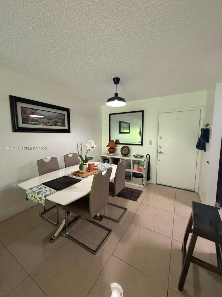 A dining room features a white table, four chairs, a mirror, and tiled flooring — 9405 W Flagler St # 212D, Miami FL 33174, MIAMI, FL