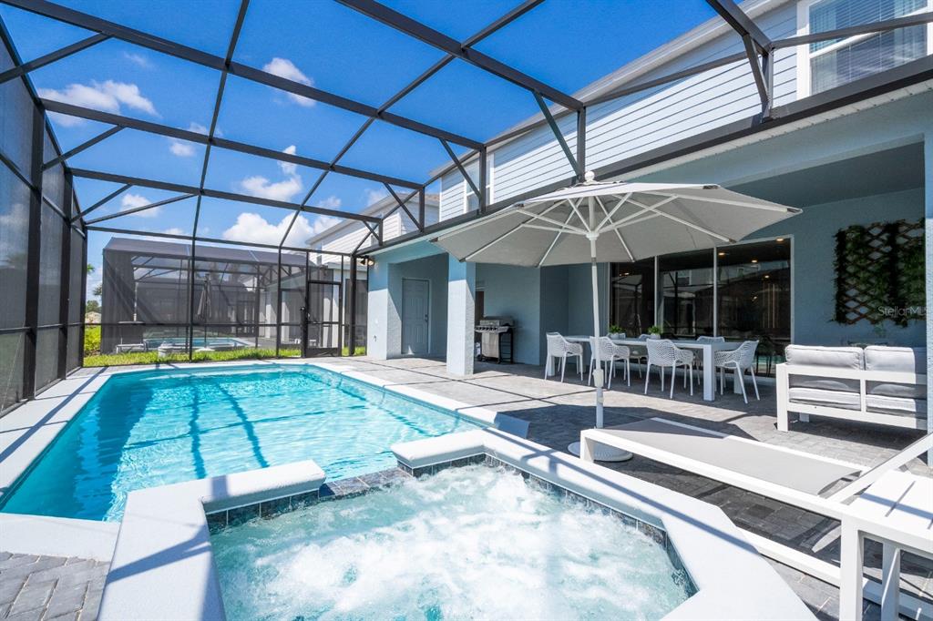 A screened-in patio features a swimming pool, a hot tub, and outdoor dining furniture — 4117 LANA AVENUE, DAVENPORT, FL