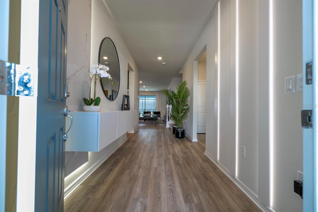 A modern entryway features wood-look flooring, a floating console table, and vertical LED wall lighting — 4117 LANA AVENUE, DAVENPORT, FL